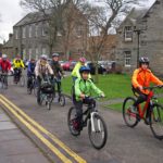 Group of cyclists in high vis cycling past houses in St Andrews