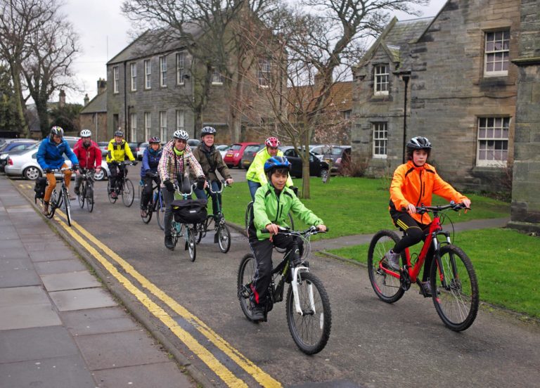 Group of cyclists in high vis cycling past houses in St Andrews