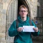 Sandy Bond holding an envelope outside building in St Andrews
