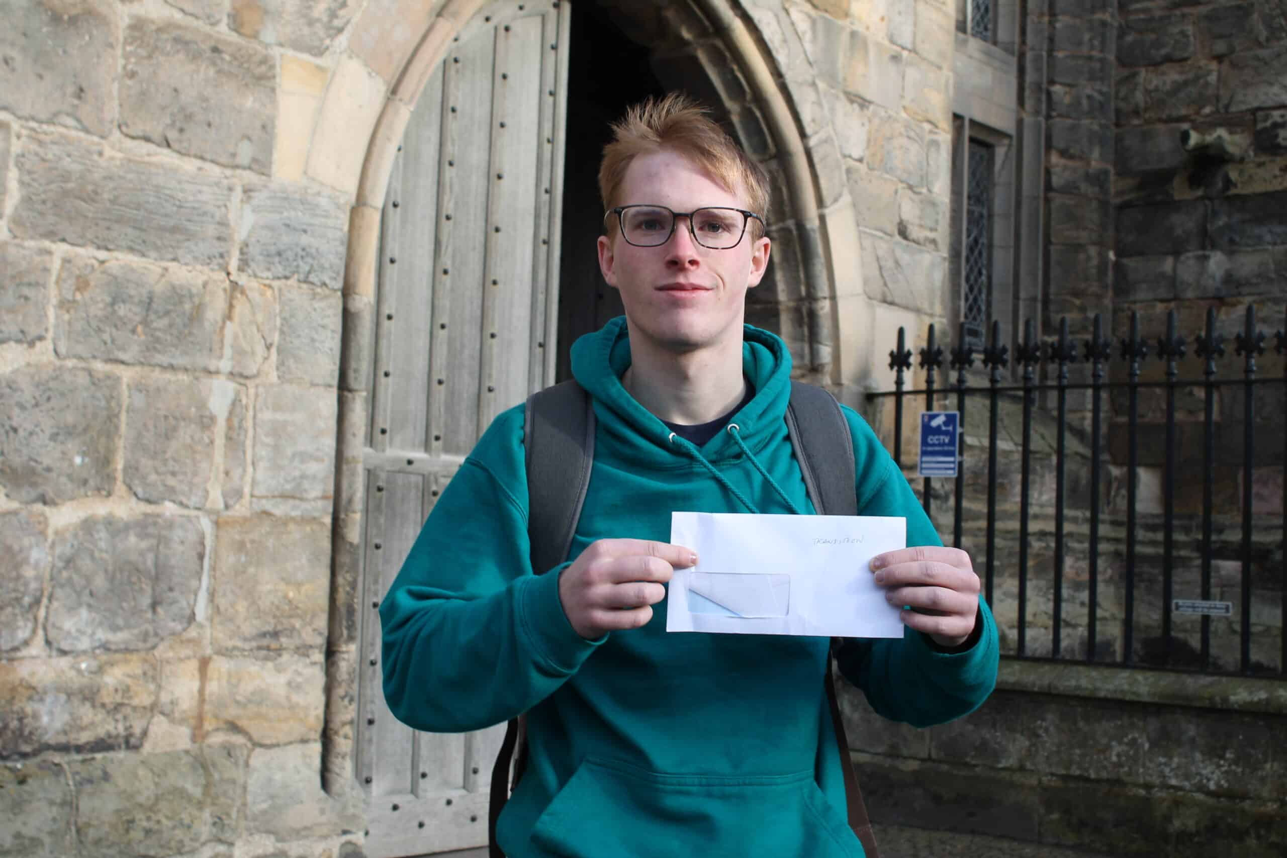 Sandy Bond holding an envelope outside building in St Andrews